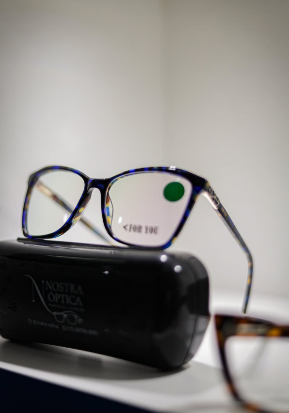 Armação de acetato estampada em azul apoiada sobre o estojo da Nostra Óptica
